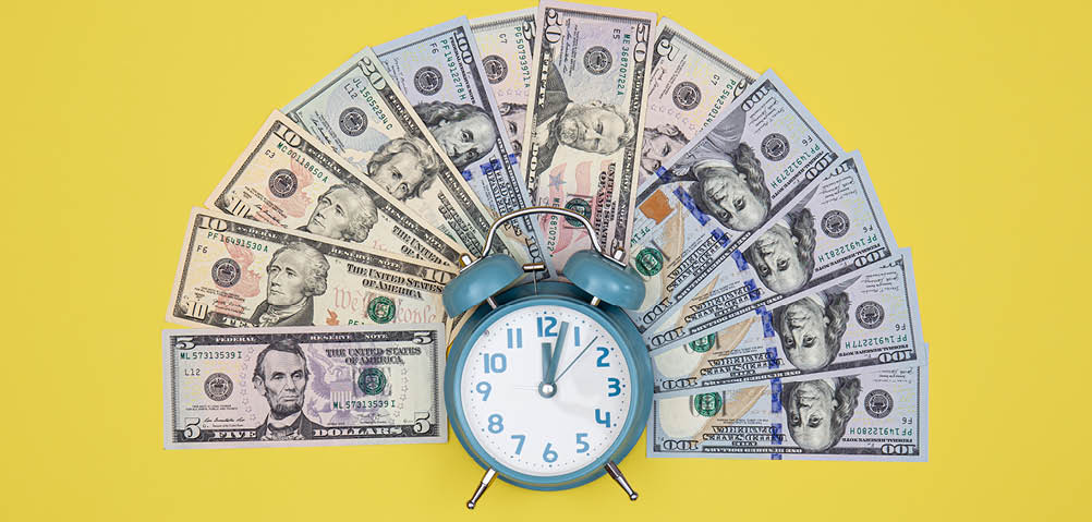 Alarm clock and money on a colored background, conceptual minimalism.