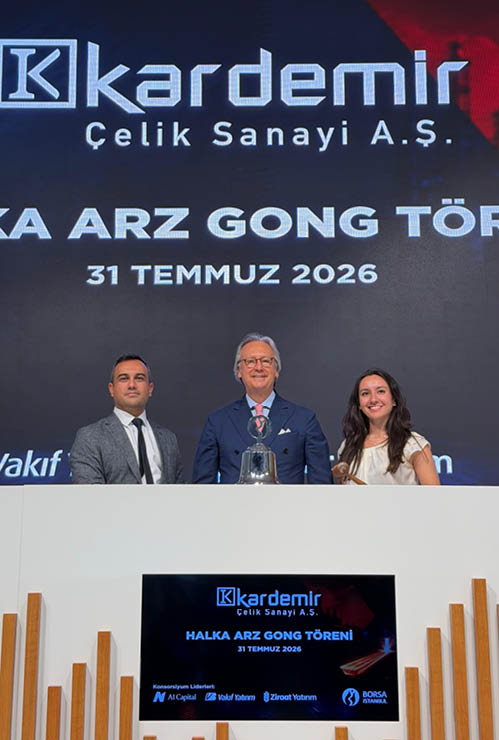 Tr s adultos vestidos formalmente est o sentados em uma mesa branca com um grande painel digital ao fundo exibindo o nome Kardemir elik Sanayi A. . e a data 31 de julho de 2026 em um evento corporativo.  Yapay zeka taraf ndan olu turulan a  klama