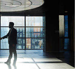 Two entrepreneurs handshaking in office center against window with sunlight penetrating inside